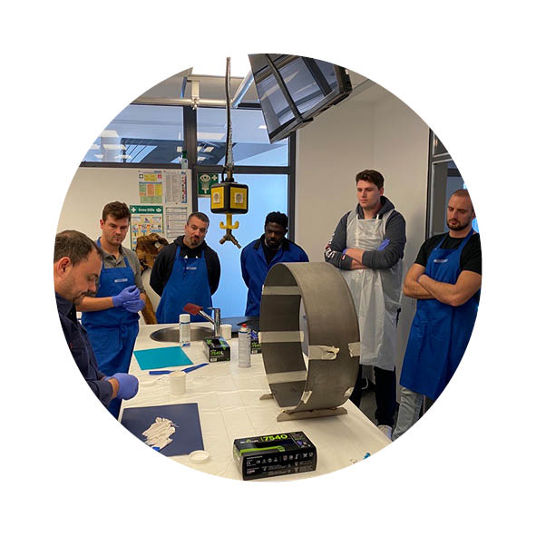 Eine Männergruppe steht in einem Labor und schauen einem Kollegen zu