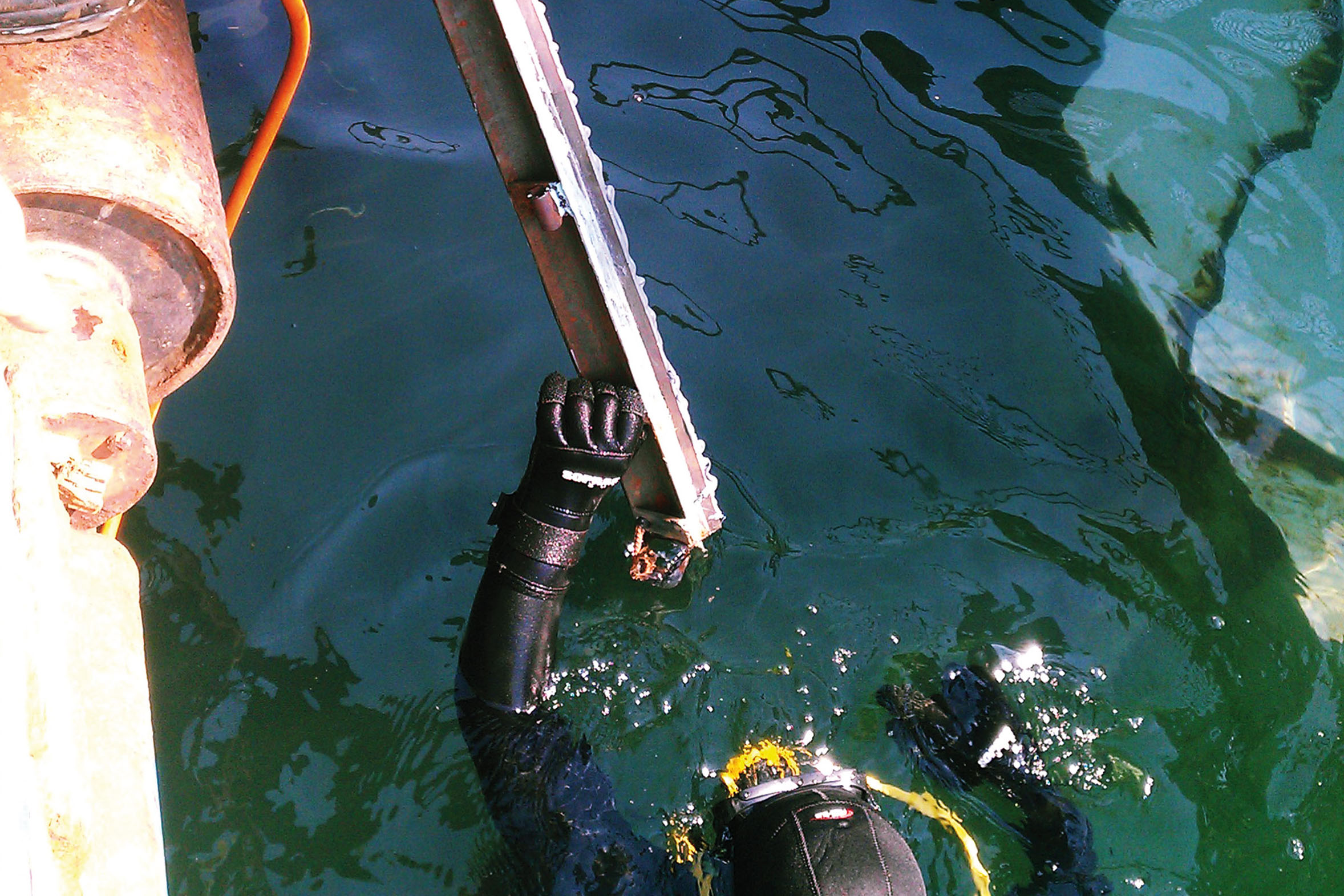 Taucher im Wasser, der ein Metallteil annimmt