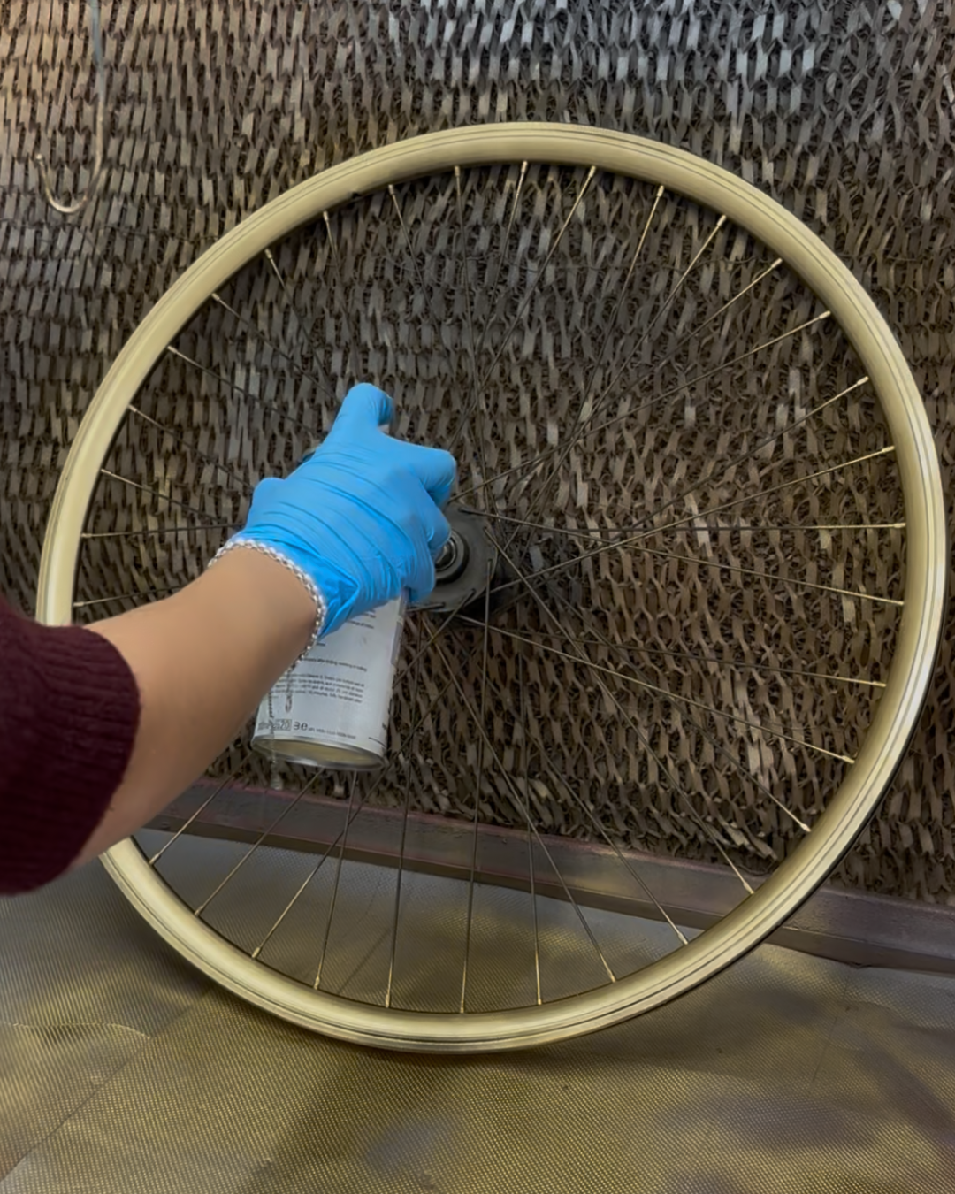 bicycle wheel, wheel rim, spray can, gloved hand, maintenance