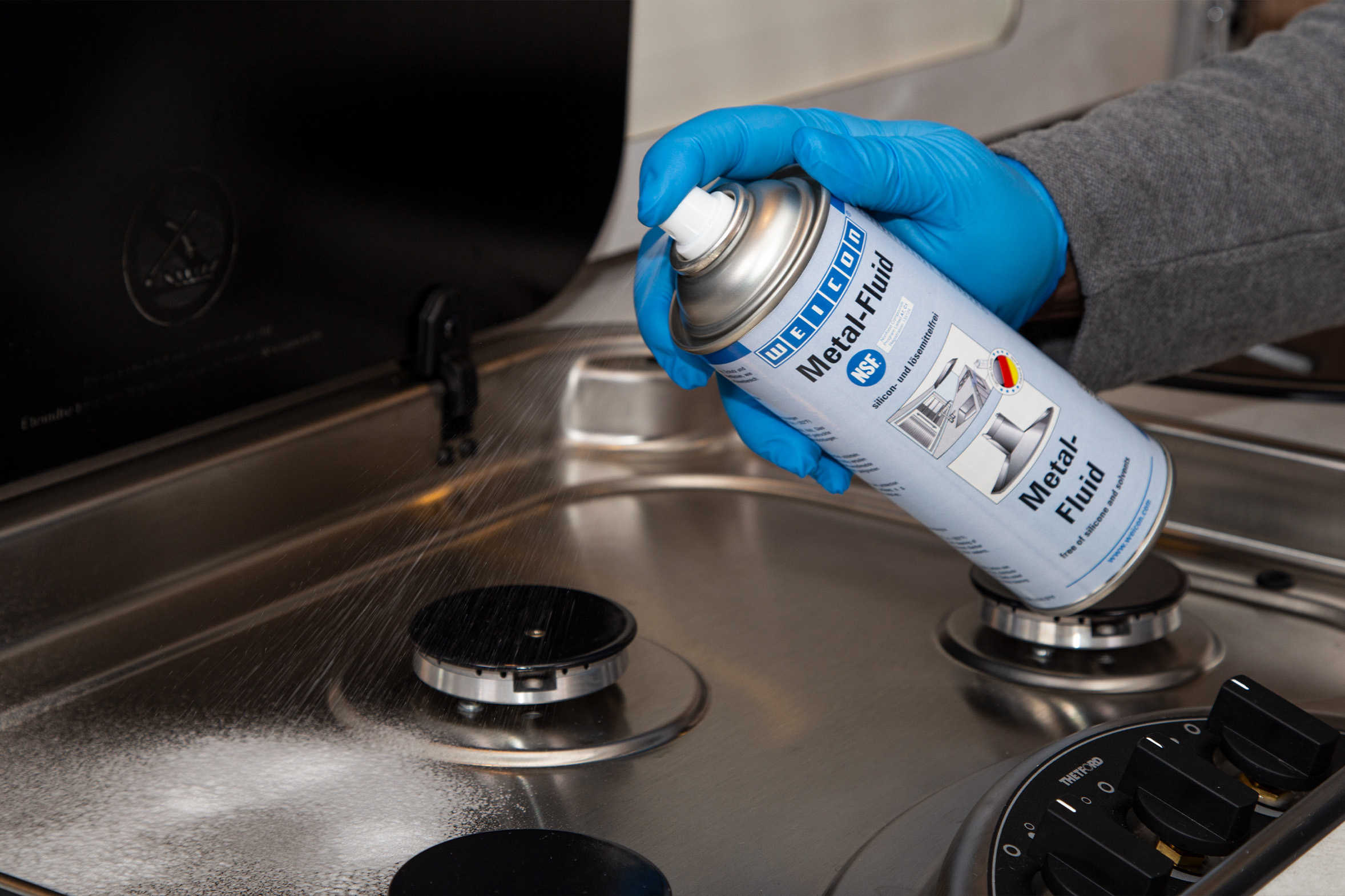 Metal-Fluid_Kueche-Wohnmobil_pflegen Weicon Metal-Fluid wird auf eine Kochplatte in einer Wohnwagenküche gesprüht