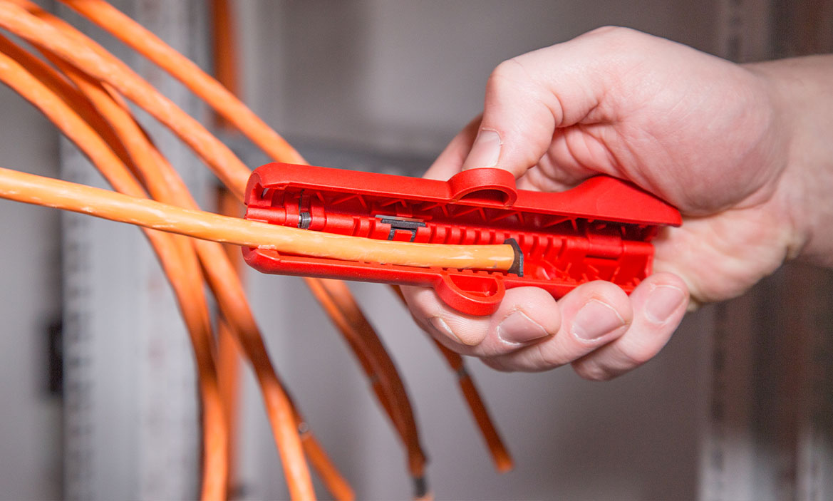 Innovation Cat Cable Stripper No. 10 Ein orangenes Kabel wird mit dem Weicon Tools Cat Cable Stripper No. 10 entmantelt