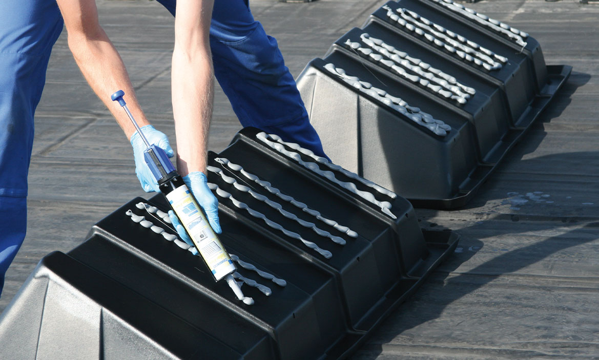 Innovationen Solar-Flex Ein Dichtstoff wird mit einer Dosierpistole auf Kunststoffboxen gegeben
