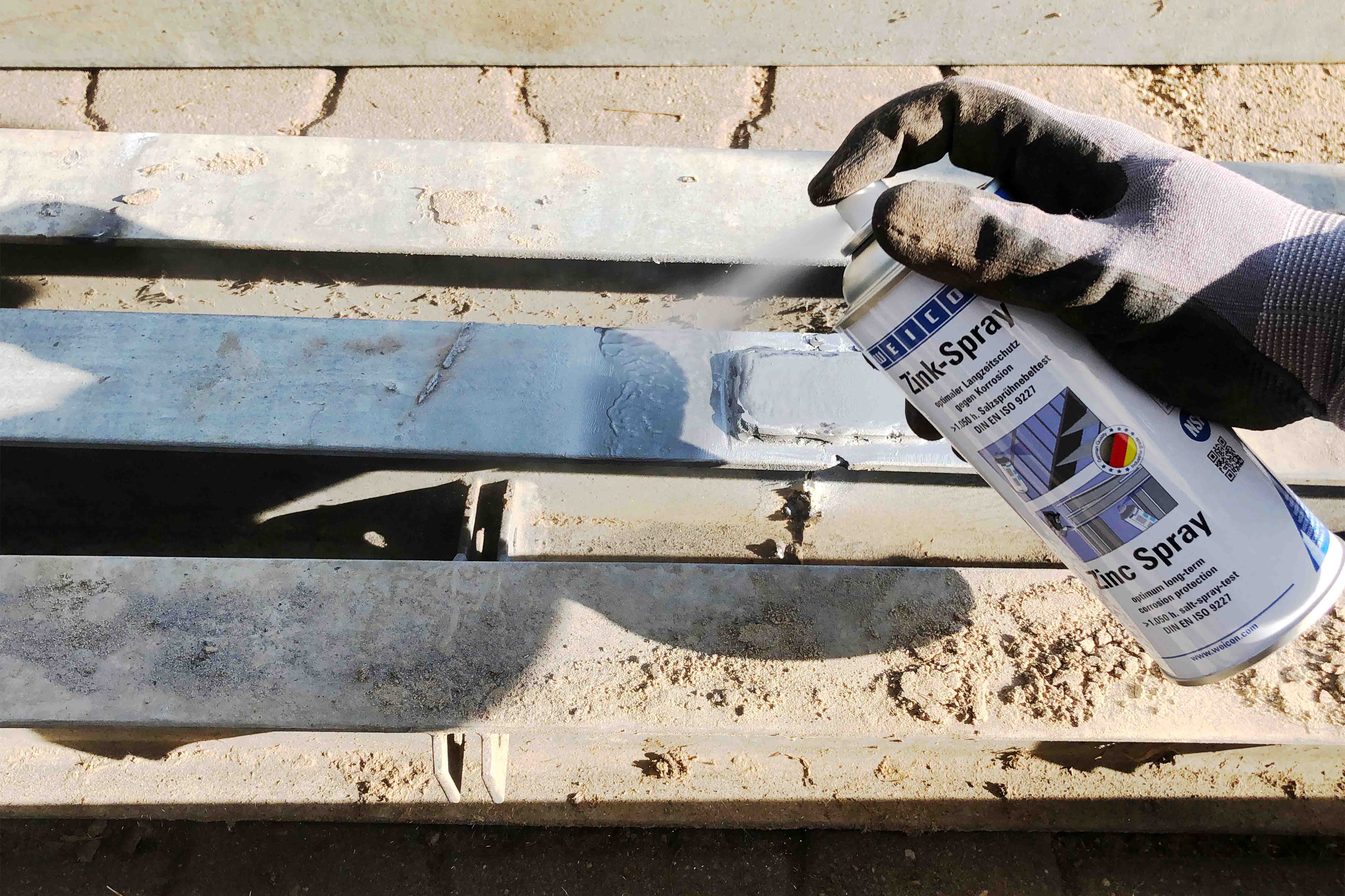 Schmale lange Metallplatten werden mit Weicon Zink-Spray besprüht