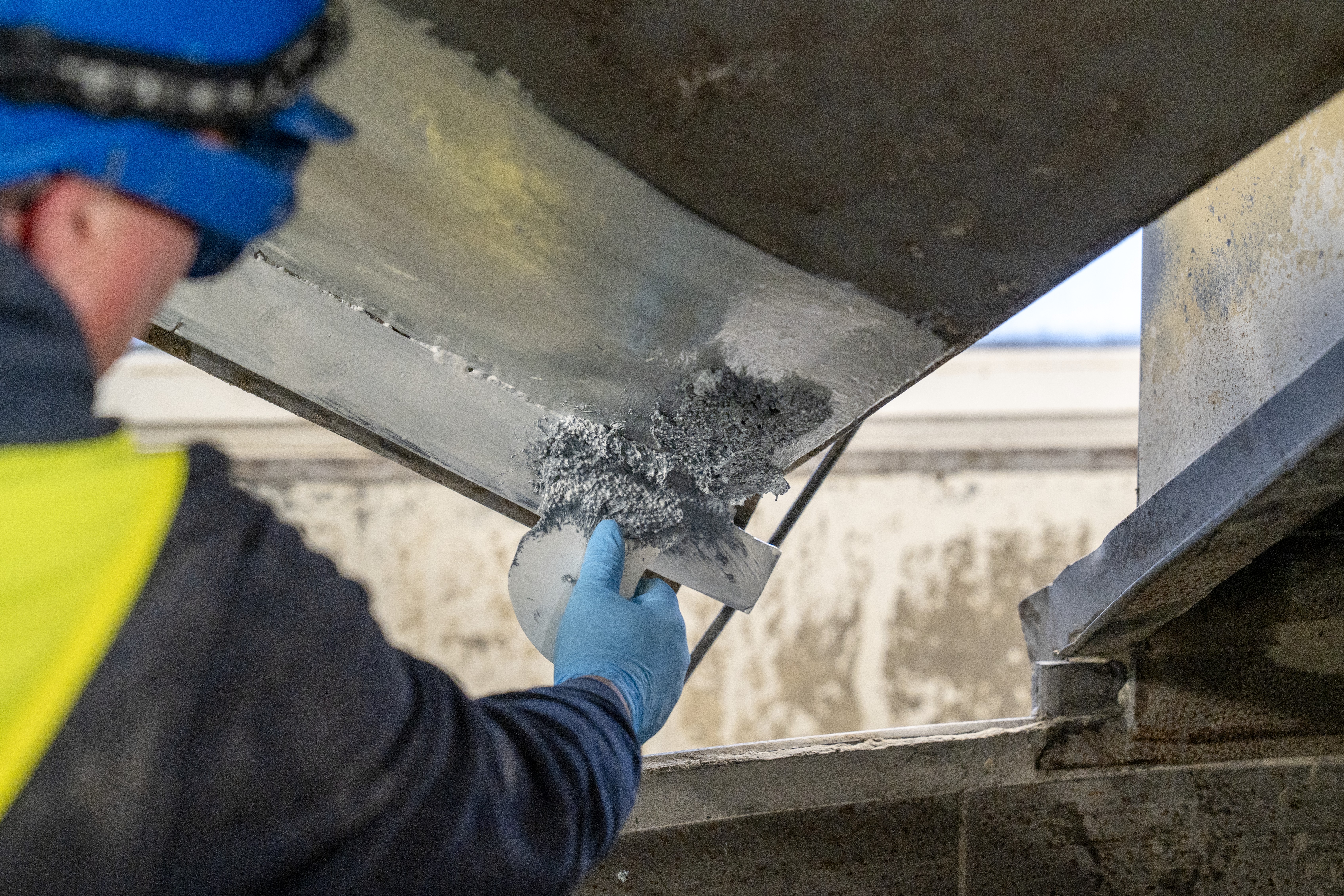 A man applicates an epoxy coating on a metal machine