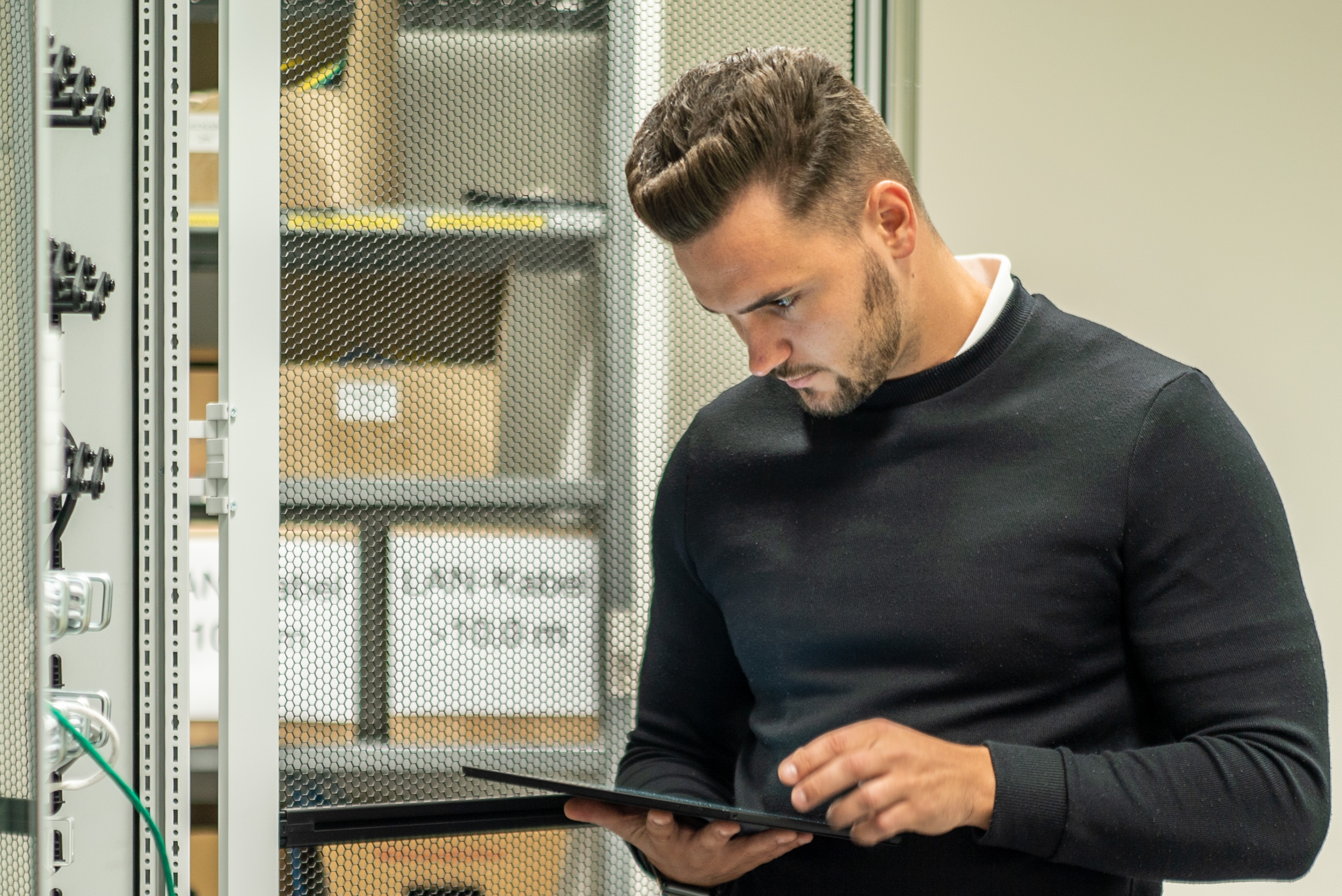 Ein Mann steht vor einem Schaltschrank und schaut auf sein Tablet